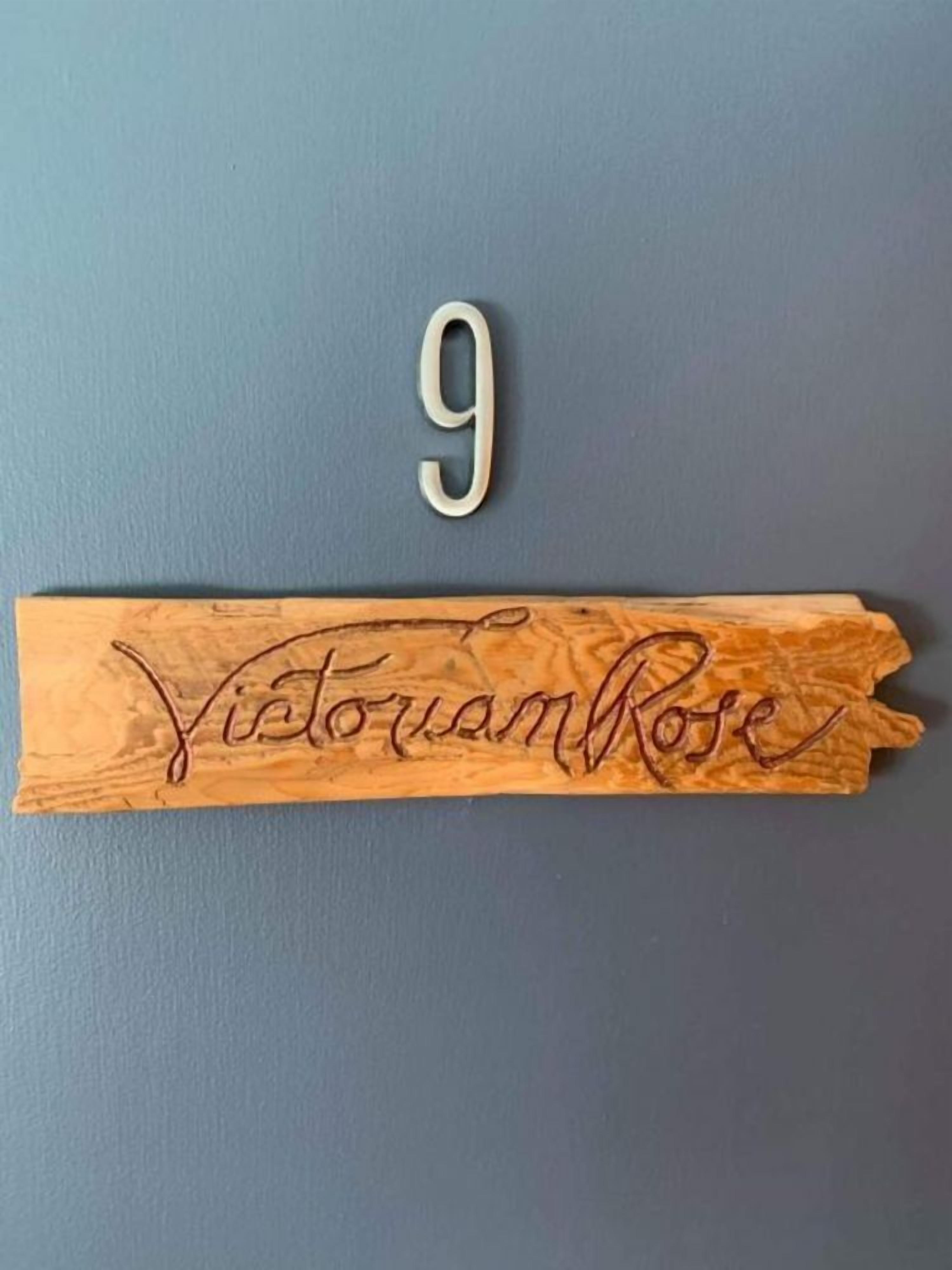 A wooden plaque with the number 9 and the name "VittouanRose" engraved on it.
