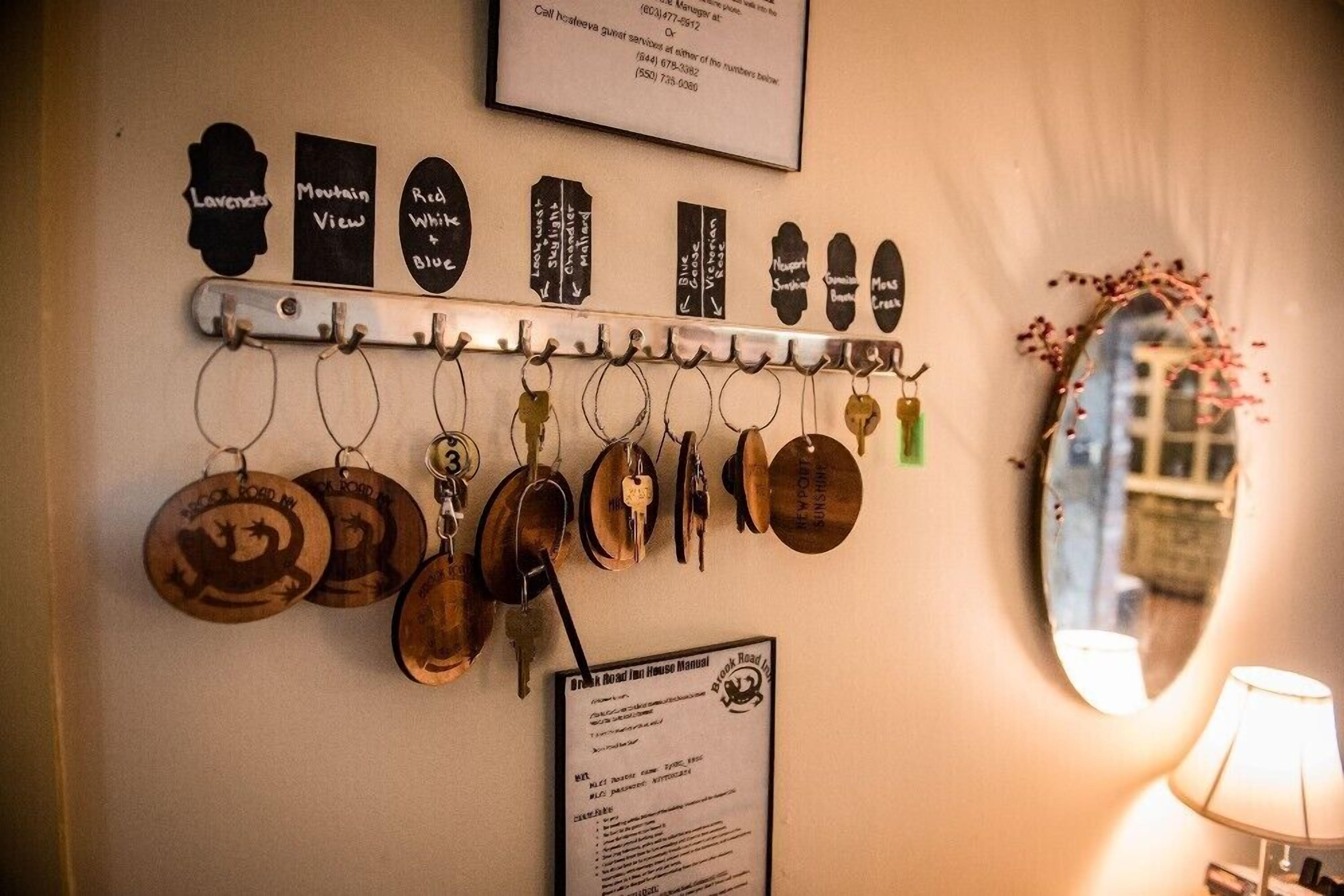 A wall with a metal rack holding keys and a sign with a list of names.