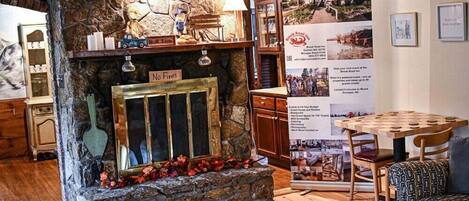 A rustic interior with a stone fireplace, wooden furniture, and a dining area.