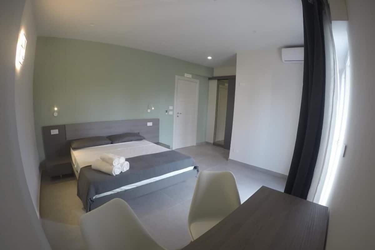 A hotel room with a bed, a desk, and a chair.