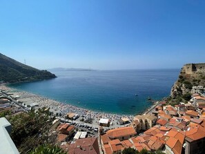 A coastal town with a beach, buildings with red-tiled roofs, and a clear blue sky. - B&Benny (Reggio Calabria)