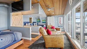 A spacious living area with a high ceiling, a large window, and a cozy seating arrangement.