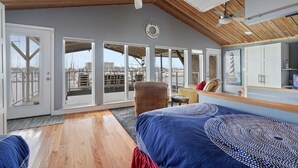 A spacious room with a high ceiling, large windows, and a view of the marina.