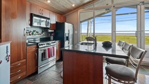 A kitchen with wooden cabinets, stainless steel appliances, and a large island with chairs.