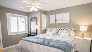 A bedroom with a bed, nightstands, a ceiling fan, and a large window. - Ski Condo on Beech Mountain (Beech Mountain)