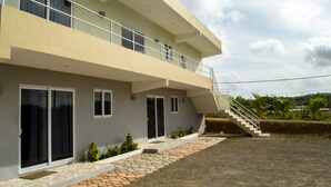 Une maison moderne à deux étages, dotée d’un balcon, d’un escalier et d’un petit jardin.