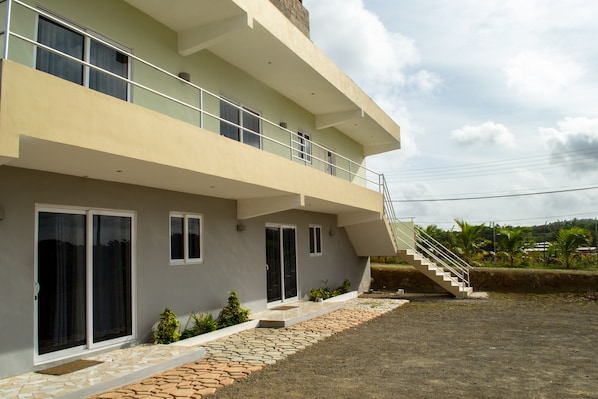 A modern two-story house with a balcony, a staircase, and a small garden area. - Group Garden Getaway (Willemstad)