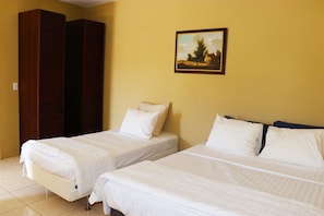 Two single beds with white linens in a room with yellow walls and a painting of a landscape. - Group Garden Getaway (Willemstad)