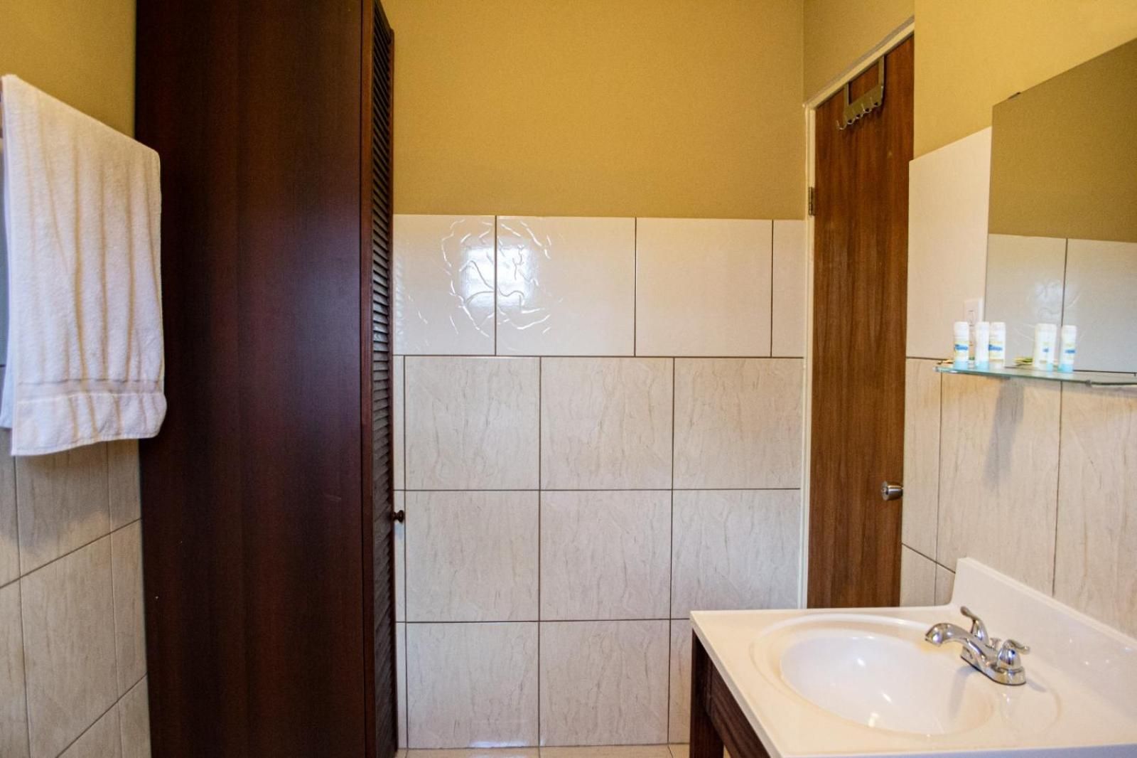 A bathroom with a white sink, a mirror, and a towel hanging on the wall.