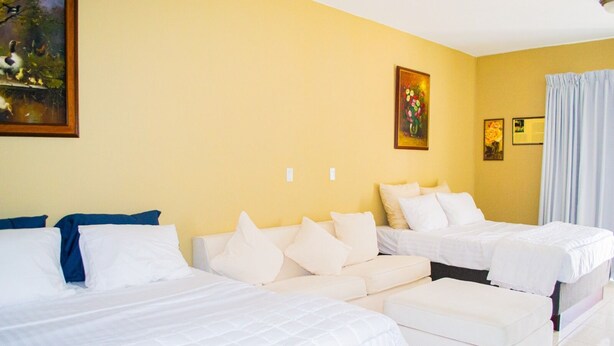 Une chambre d’hôtel avec deux lits, un canapé et un tableau au mur.