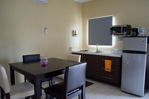 A compact kitchen with a dining table, chairs, a refrigerator, a microwave, and a coffee maker. - Group Garden Getaway (Willemstad)