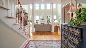 A spacious living area with a wooden staircase, a sailboat model, and a decorative lamp.