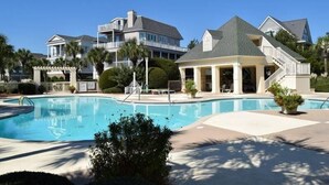 A swimming pool surrounded by a resort-style building with a covered patio area.