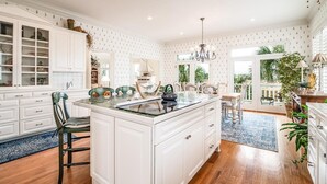 A spacious kitchen with white cabinetry, a central island, and a view to a balcony.