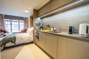 Experience a stylish atmosphere in this room with a large bed, compact kitchenette, and large window.
