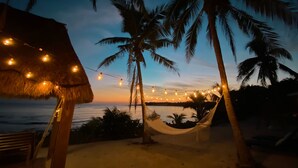 Eine Strandansicht mit einer Hängematte, Palmen und Lichterketten.