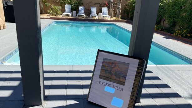 Ein Poolbereich mit Liegestühlen und einem Schild mit der Aufschrift 'Desert Villa'.