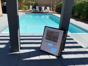 Een zwembadgedeelte met ligbedden en een bord waarop 'Desert Villa' staat.