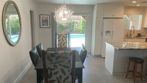 Eine moderne Küche mit weißen Schränken, einer zentralen Kochinsel und einem Essbereich mit Tisch und Stühlen.
