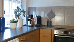 A modern kitchen with wooden cabinets, a built-in oven, and a coffee maker.