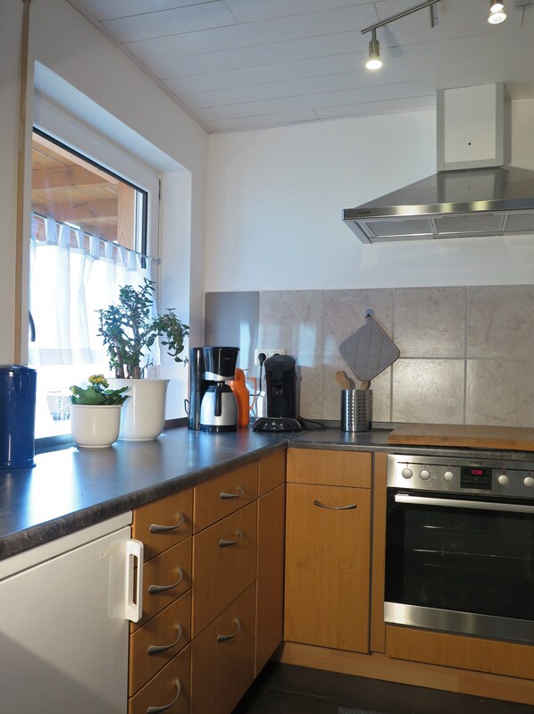 A modern kitchen with wooden cabinets, a built-in oven, and a coffee maker.