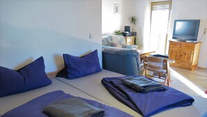 A room with two beds, a sofa, a TV, and a wooden cabinet.