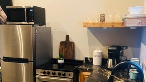 A kitchen with stainless steel appliances, a black marble countertop, and a wooden shelf above the sink. - Gone West Ranch cabin in Fredericksburg  (Fredericksburg)
