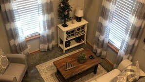 A living room with a sofa, a coffee table, a TV, and a small Christmas tree. - Gone West Ranch cabin in Fredericksburg  (Fredericksburg)