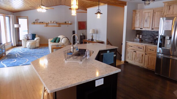 A modern kitchen with a large island, wooden cabinets, and a built-in dishwasher. - Beautiful 4 BDRM Retreat on Loon Lake with Sauna and Sand Beach! (Cohasset)