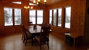 A wooden-paneled room with a large dining table, chairs, and a chandelier. - Beautiful 4 BDRM Retreat on Loon Lake with Sauna and Sand Beach! (Cohasset)