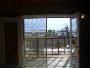 A sliding glass door leading to a balcony with a view of a snowy landscape and trees. - Romantic modern cabin overlooking lake beckwith (Pueblo)