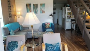 Un salon confortable avec un canapé, des fauteuils, une table basse, une lampe et une bibliothèque.