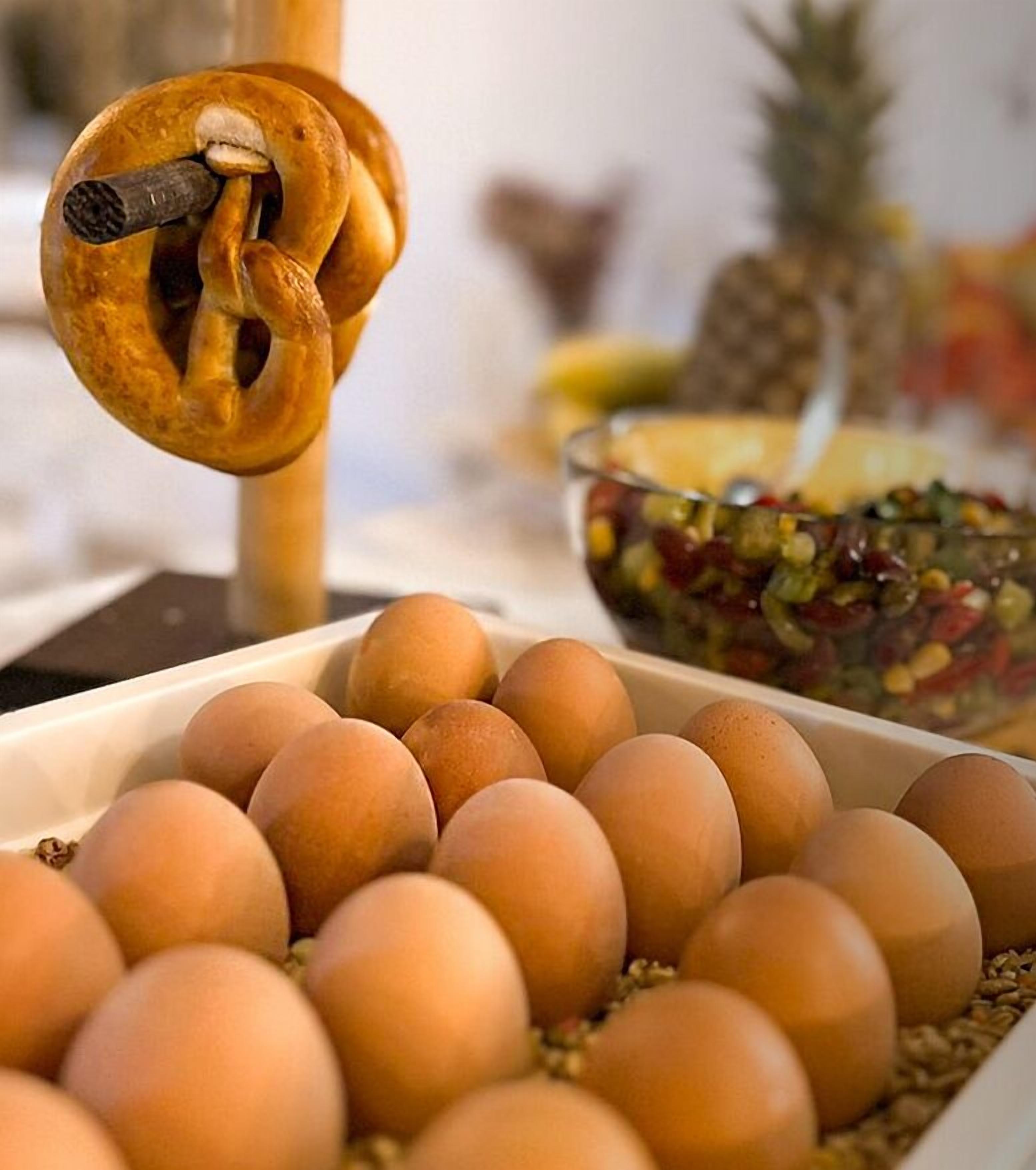 A tray of eggs and a wooden tool with a hook.