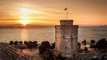 A historic tower by the sea during sunset.