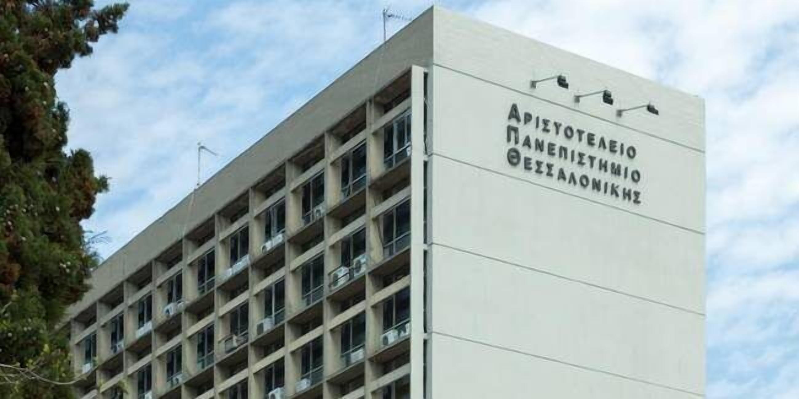 A building with multiple floors and balconies, featuring a sign with text in a foreign language.