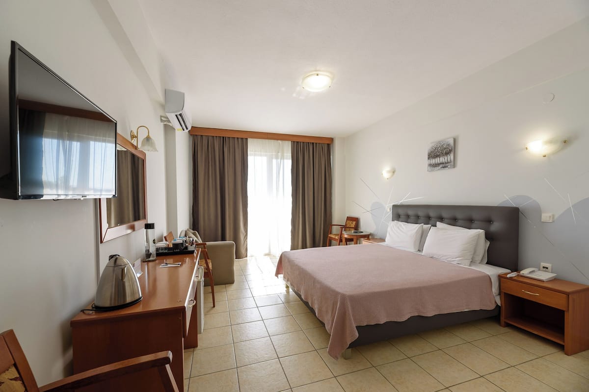 A hotel room with a bed, a desk, a chair, a television, and a window with curtains.