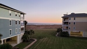 Zona residencial con dos edificios de varios pisos, césped cuidado y vista al mar.