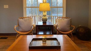 Una habitación acogedora con dos sillones de mimbre, una mesa de madera y una lámpara.