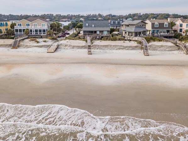 A beachfront property with multiple houses, a sandy beach, and a staircase leading to the beach. - Oceanfront Escape with Beach Access (Pawleys Island)