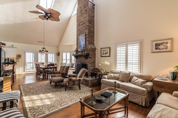 A spacious living room with a high ceiling, a fireplace, and a dining area.