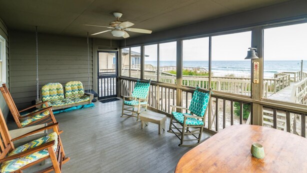 A covered outdoor area with wooden furniture, a ceiling fan, and a view of the ocean. - Oceanfront Escape with Beach Access (Pawleys Island)