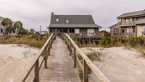 A wooden boardwalk leading to a beachfront house with a balcony. - Oceanfront Escape with Beach Access (Pawleys Island)