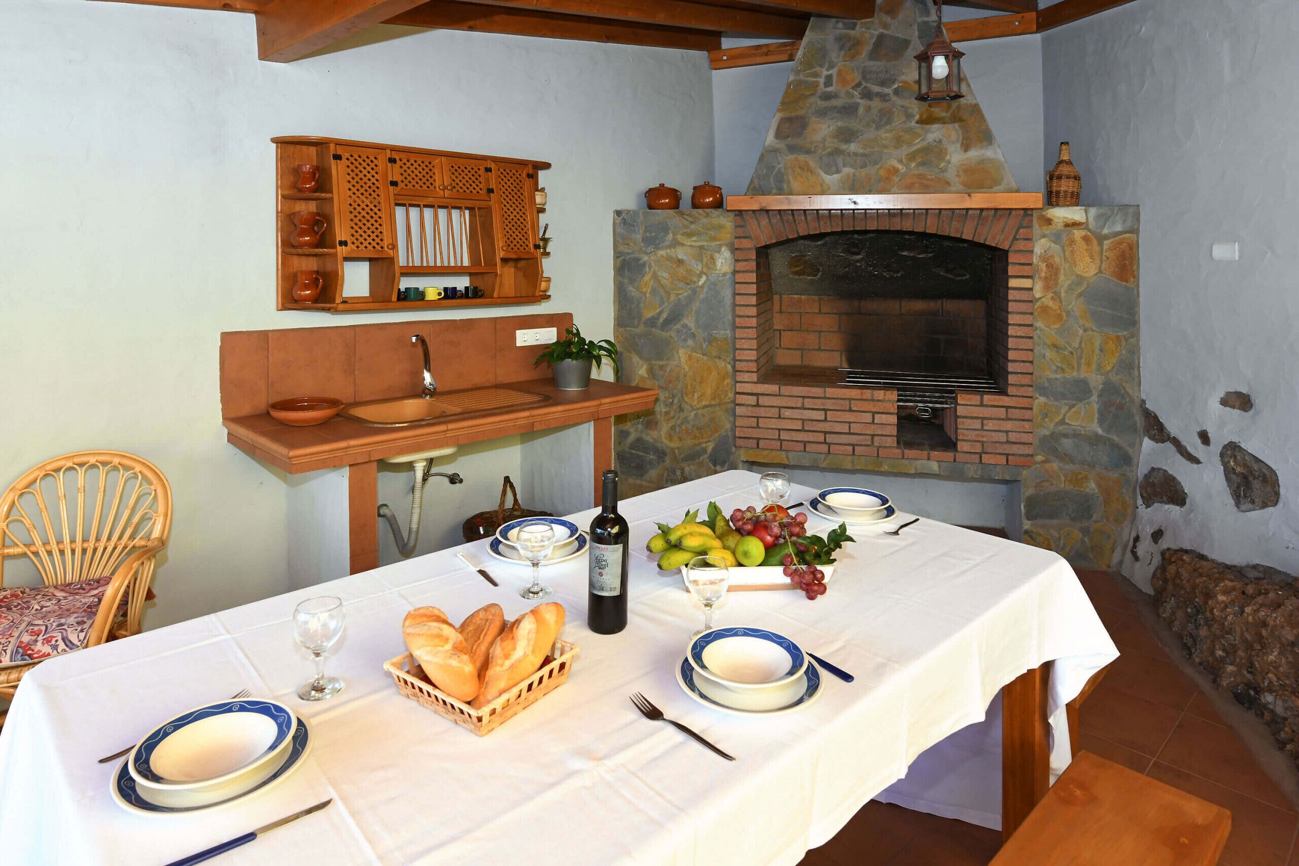 Un comedor con chimenea de piedra, armarios de madera y una mesa dispuesta para una comida.