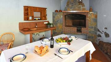 Un comedor con chimenea de piedra, armarios de madera y una mesa dispuesta para una comida.