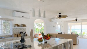 A spacious kitchen with a central island, modern pendant lights, and a ceiling fan. - Beachfront CASA PAAMUL Riviera Maya-Tulum (Paamul)