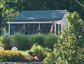A house with a covered porch, a flag, and a well-maintained garden.
