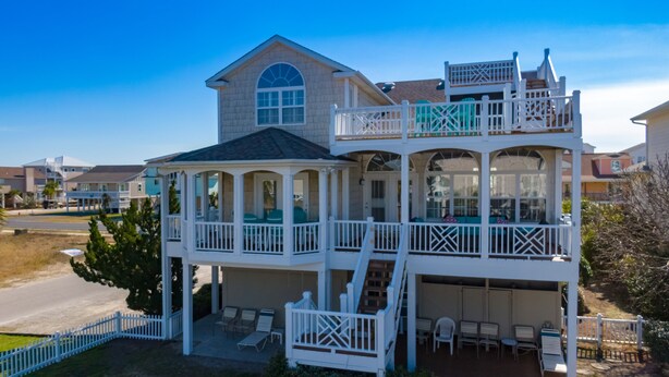 A two-story house with a balcony, a covered porch, and outdoor seating.
