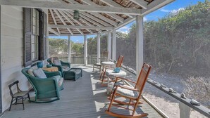 A covered porch with wicker furniture and a view of the surrounding landscape. - Lemon LaBruce 6 Bdrm Oceanfront Beach House (Pawleys Island)