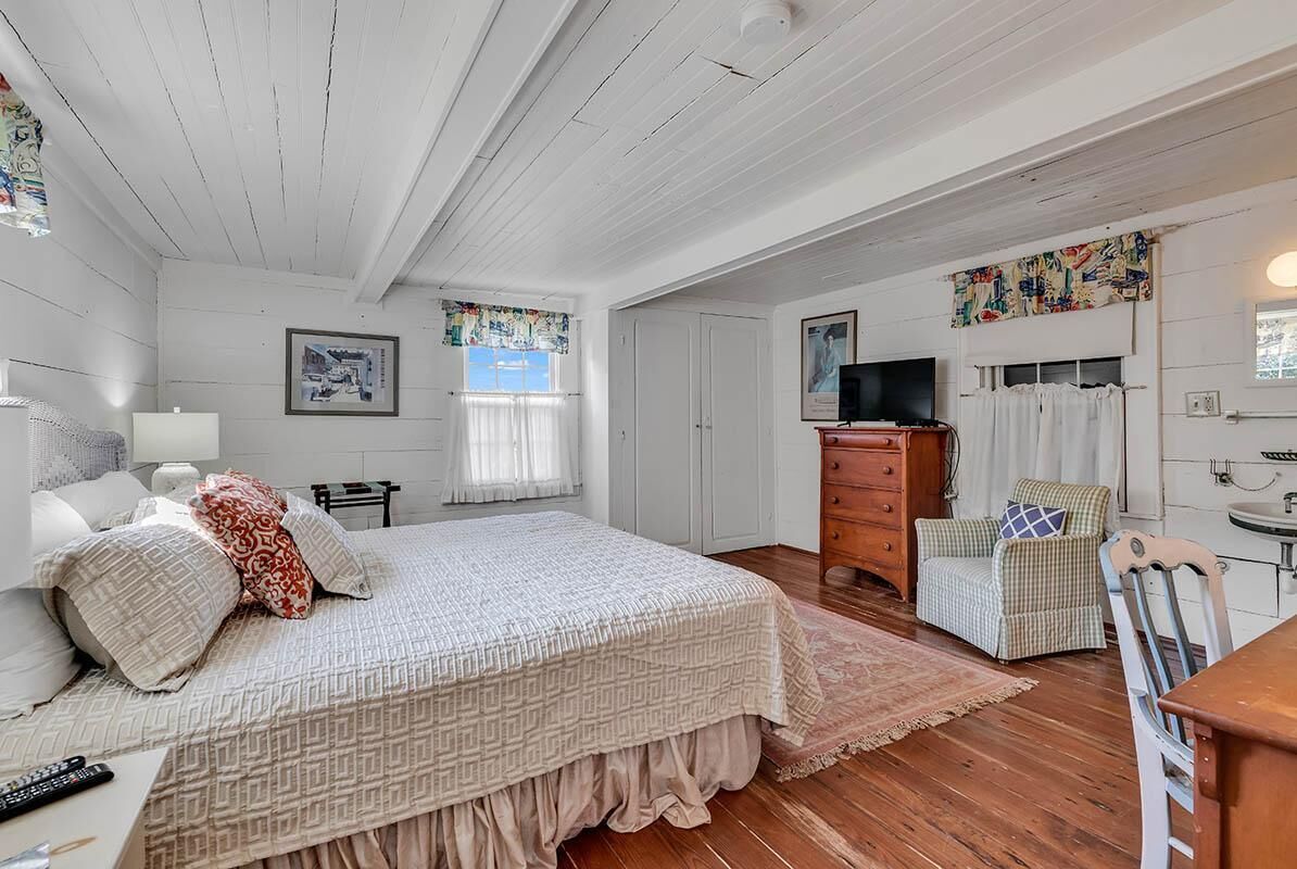 A bedroom with a bed, dresser, chair, and a television.