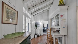 A narrow hallway with wooden floors and white walls, leading to a dining area with a wooden table and chairs. - Lemon LaBruce 6 Bdrm Oceanfront Beach House (Pawleys Island)